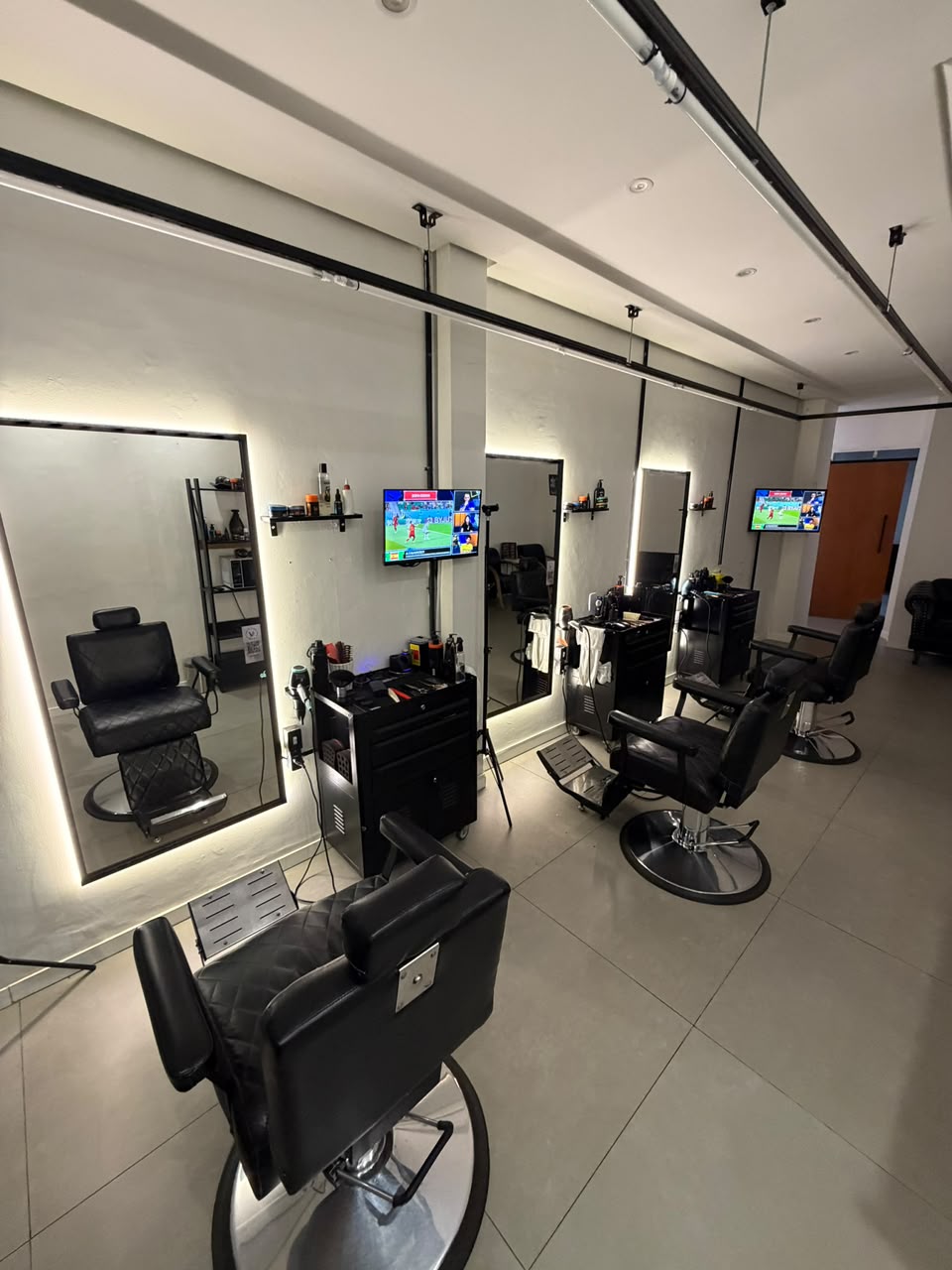 Salão da Barbearia do Vini, com cadeiras, espelhos com luz de LED e TVs